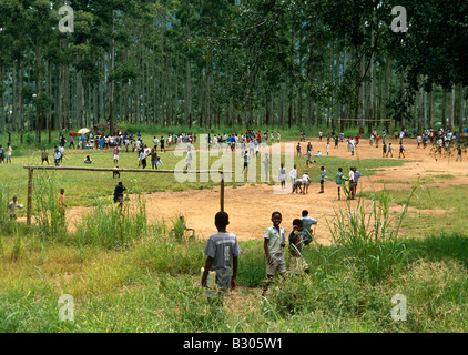 Crowds of schoolchildren playing on school playing field in rural forest, Uganda, Africa Stock Photo