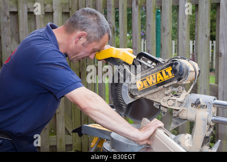 Man using a De Walt circular saw power tool to cut a piece of wood outside. UK Britain Stock Photo