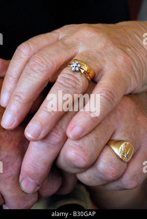 a mature couple's hands showing their golden wedding rings with one hand on top of the other Stock Photo