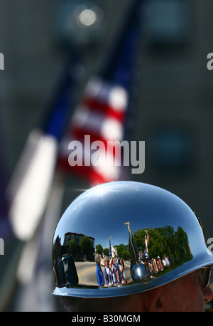 A crowd is reflected in the shiny helmet of a soldier during a Memorial Day Parade with an American flag in the background.