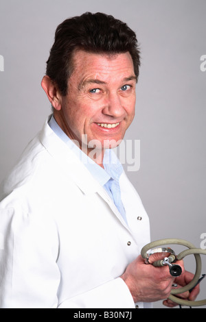 Male 40 something doctor smiling holding a stethoscope wearing a white coat Stock Photo