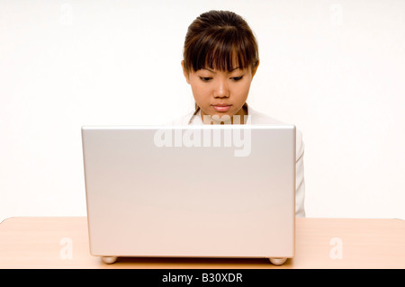 A cute young asian businesswoman works on a laptop computer Stock Photo