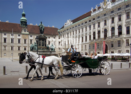 inner courtyard of the Hofburg (in der Burg) in Vienna with a fiaker passing with passengers and statue of Kaiser Franz I Stock Photo