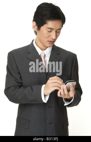 An asian businessman makes notes on his electronic organiser Stock Photo