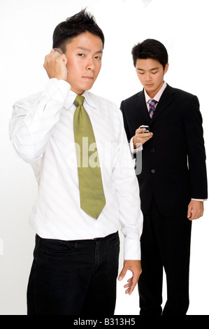 Two asian businessmen using their phones to communicate in different ways Stock Photo