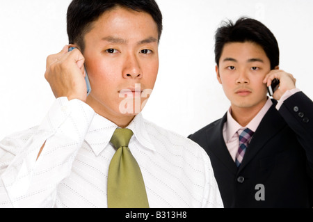 Two young asian businessmen using their phones Stock Photo
