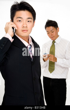 Two asian businessmen using their phones to communicate in different ways Stock Photo