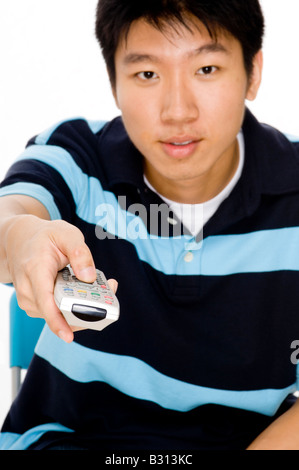 A young man points remote control at the tv (focus on remote) Stock Photo