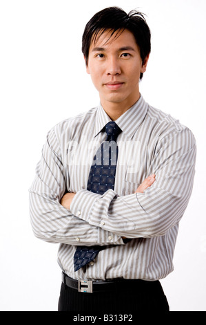 A confident young businessman stands with arms folded Stock Photo