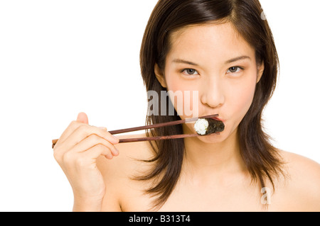 A pretty young girl bites into a sushi roll Stock Photo