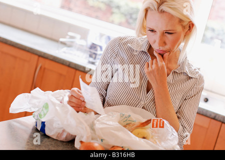 woman looking shocked at a receipt for vegetables Stock Photo