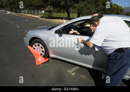 Driving instructor points out crushed cone to teen driver Stock Photo