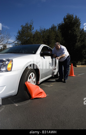 Driving instructor points out crushed cone to teen driver Stock Photo