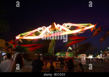 Chairoplane flying whirl funfair ride.  Mass of moving whorling color horizontal to the ground with few lights from fair in back Stock Photo