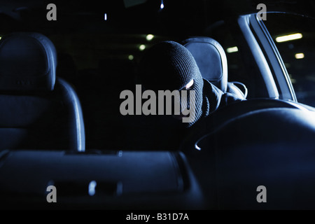 Front profile of masked thief stealing car Stock Photo