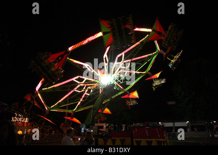 Chairoplane flying whirl.  Up at 45 degree angle.  Bands of revolving light with others blocked out by kites above riders. Stock Photo