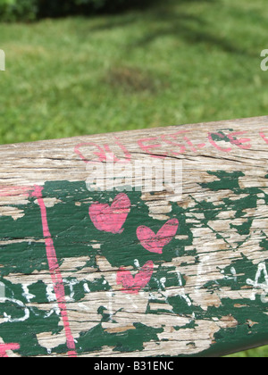 three love hearts painted on old green park bench Stock Photo