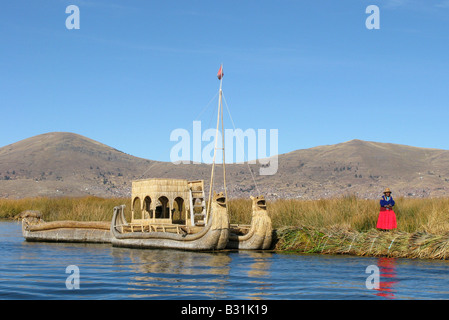 A Uros women near a reed boat on self-fashioned floating reed islands in Lake Titicaca, Peru Stock Photo