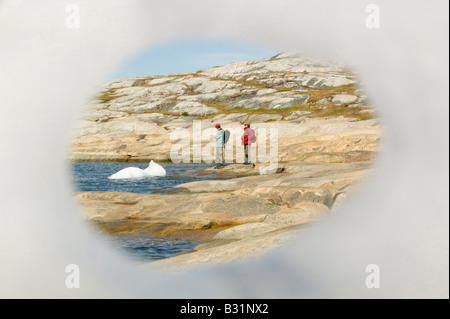 Looking through a hole in an iceberg at Ilulissat on Greenland with icebergs from the Jacobshavn icefjord behind Stock Photo