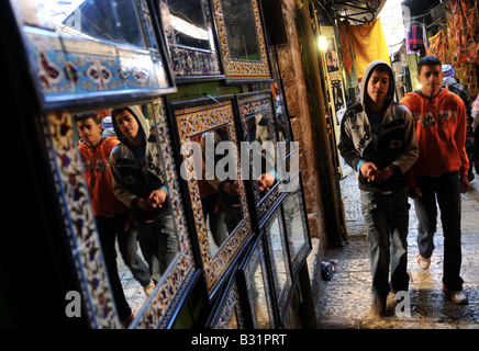 Two young modern Palestinian Arab boys walk through dark alleyways of the market in the Arab Quarter of Jerusalem's Old City. Stock Photo