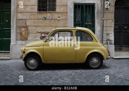 Rusting mustard-yellow Fiat 500 parked in Via del Mascherino, central Rome, Italy Stock Photo
