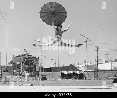 Female acrobat doing splits on tightrope Stock Photo