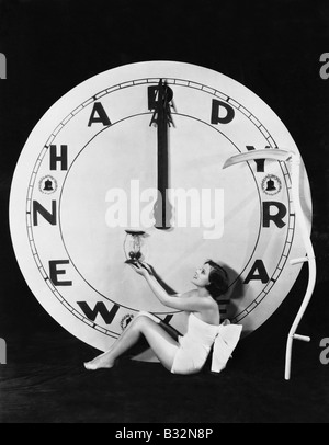 Woman with clock at midnight on New Years Eve Stock Photo