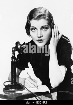 Portrait of woman on telephone taking notes Stock Photo