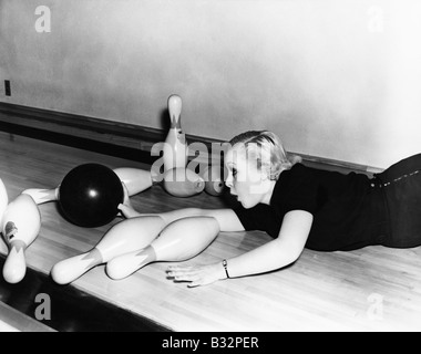 Woman sliding down bowling alley with ball Stock Photo