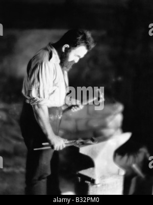 Blacksmith working metal on anvil Stock Photo