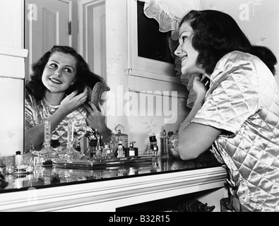 Young woman brushing hair at dressing table