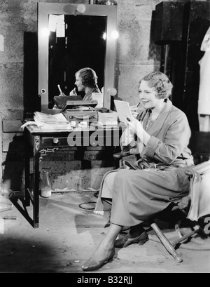 Woman applying lipstick in her dressing room Stock Photo