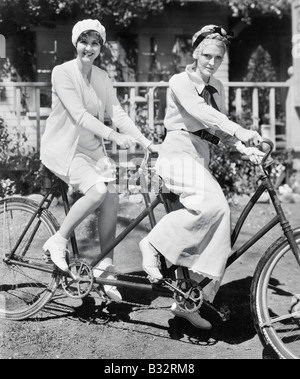 Portrait of two young women sitting on a tandem bicycle Stock Photo