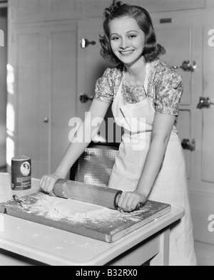 Young woman rolling out dough in the kitchen Stock Photo