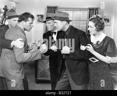 Two men fighting with each other and being held back by a woman and a man Stock Photo