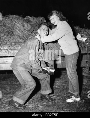 Portrait of a young man helping a young woman board a trailer Stock Photo