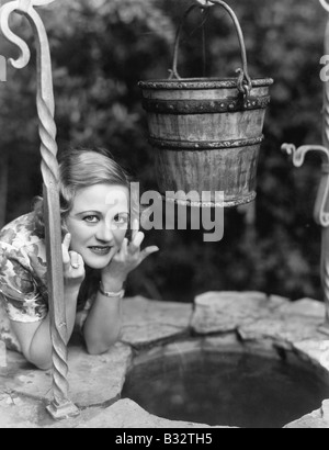 Portrait of a woman leaning on a well with her finger crossed Stock Photo