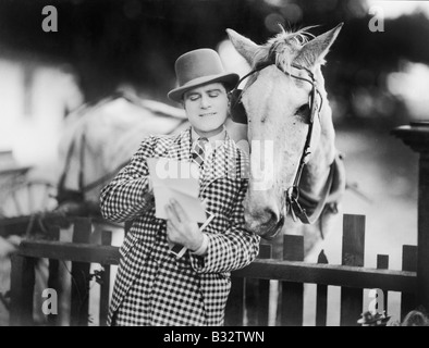 Man leaning against a fence reading a letter to his horse Stock Photo