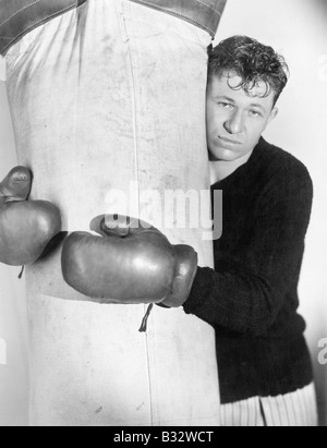Man in boxing gloves hugging the punching bag Stock Photo
