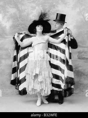 Man in a top hat helping a woman into a cape Stock Photo