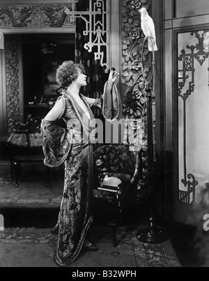 Young woman standing and talking to her parrot Stock Photo