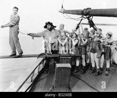 Group of pirates trying to push a young man over a plank Stock Photo