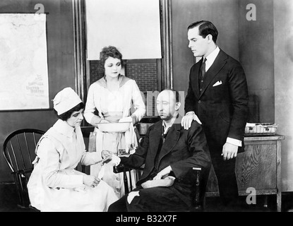 Patient and two nurses attending him and a friend comforting him Stock Photo