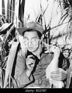 Young  smiling man holding a duck Stock Photo