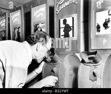 Man looking into a nickelodeon film machine Stock Photo