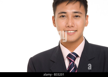 A young asian businessman in a sharp navy blue suit with matching pink shirt and tie Stock Photo