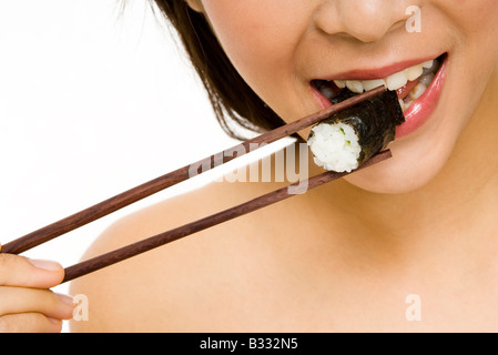 A young woman bites into a sushi roll Stock Photo