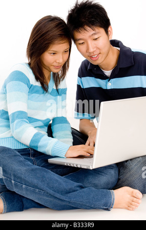 A happy young couple sitting on floor using laptop computer Stock Photo