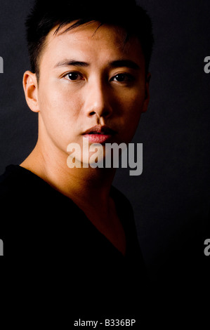A moody portrait of an asian male model in black on black Stock Photo