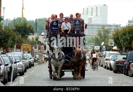 A group of tourists take a ride on a massive horse-drawn carriage, through the quaint streets of Antwerp, Belgium. Stock Photo